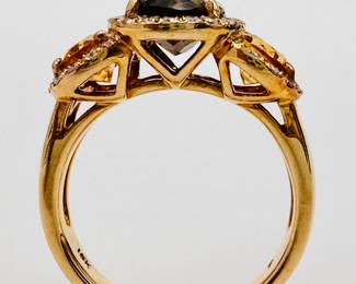 Closeup of 18k yellow gold ring with a central smoky quartz flanked by two citrines, each stone encircled by diamonds