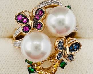 Closeup of the lovely 18k yellow gold ring featuring a large pair of pearls with gem set butterflies and diamond accents