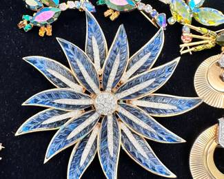 An incredibly glamorous and large Crown Trifari flower brooch, blue with white rhinestones, shown with some AB crystal brooches marked Austria