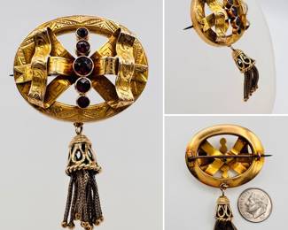 Antique 19th century 15ct gold and garnet brooch, oval form with a vertical row of bezel set garnets on a bow crafted in dimensional ribbons. Engraved with all over pattern, and suspending a chain and beaded tassel.