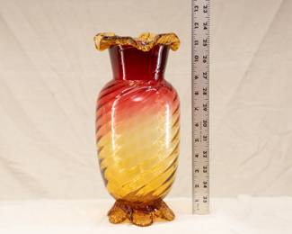 A large 11.5 inch hand blown amberina glass vase with swirled optic rib body, ruffled rim, atop applied amber glass tabbed feet 
