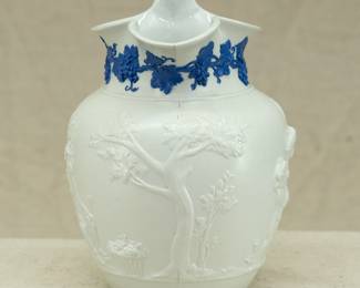 Another view of the antique Wedgwood "Bacchanalian Boys" pitcher, white jasper, decorated with Classical imagery of young boys and satyrs in Bacchic revelry (with grapes and grape leaves in their hair.) On one side, a young Bacchus holding his thyrsus (fennel staff) is being held aloft by two other boys, a vessel of wine beside them; the other scene has a satyr and young Bacchus sitting beneath a tree. The neck of the pitcher has applied blue sprig band of fruiting grape vines. Marked with "WEDGWOOD" to the base, dating 1790 to 1820. The design is based on drawings sent to Josiah Wedgwood by artist Lady Diana Beauclerk, née Spencer (1734-1808), daughter of the 3rd Duke of Marlborough.