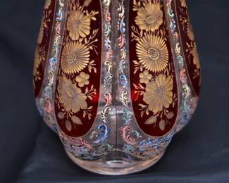 Closeup of the stunning and large antique Bohemian art glass vase (Moser? Harrach?) intricately painted overall with acanthus leaf scrolls in polychrome enamel, with cranberry glass panels containing wheel carved gilded flowers, and gold gilding at the flared rim.