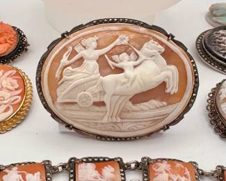 Closeup of the beautiful carved natural stone (and coral and shell) cameo brooches and delicate necklaces, and a gorgeous antique silver linked cameo bracelet