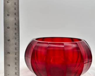A Chinese Peking Glass ruby red bowl, compressed globe form with curved, faceted sides. The base is engraved with a four-character Qianlong mark within a square.