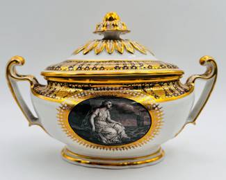 A view of the rare Worcester Porcelain (Flight) lidded sauce tureen (not showing the with included stand) from the ‘Hope service’ circa 1792, signed with blue crowned script Flight and open crescent marks, painted by John Pennington. The celebrated 'Hope' service was commissioned by the Duke of Clarence and St Andrews (later King William IV), in January 1790, and was completed just over a year later. The Neo-Classical service consists of a soft-paste porcelain base, with a bold blue underglaze lobed border, with gilt patterae, and gilt arched panels and stars. The centre cartouche artwork features the Greek mythological Hope, painted in monochrome using the French-inspired grisaille style. Across the set, Hope is depicted in a variety of poses with an anchor, and often with a ship in the distance.