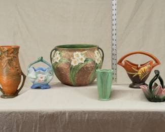 Art Pottery: A Roseville Pottery orange Bushberry vase, 1940s; a Weller Pottery Roba pattern basket vase, 1940s; a Roseville Pottery Jonquil planter, a Brush-McCoy art deco green matte glaze leaf vase, a Roseville Pottery brown tangerine Freesia vase, and a Hull Pottery leaves and berries planter basket