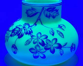 Seen by black light: Antique Harrach or Thomas Webb & Sons cameo glass vase circa 1890, cased blue over creamy white uranium glass, cameo cut around the body with flowering petals on leafy vines. A banded blue rim at the top and a polished pontil on the base. 