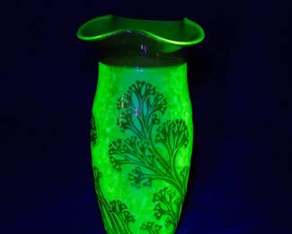 Under black light: A 19th century Val St Lambert art glass vase, cased uranium glass, with a three-lobed rim; cranberry glass outer layer acid-etched to create a graceful seaweed decoration. Produced around 1897.