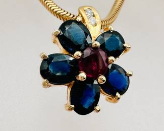 Closeup of 14k yellow gold diamond and colored gemstone flower pendant necklace