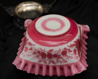 Closeup of the antique bride's basket with cameo glass bowl of pink and white cased glass, square form with floral motif and flared ruffled edge; and silver plated metal basket handle stand by Rockford Silver Co. Illinois