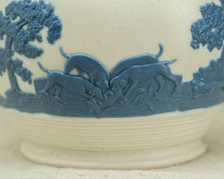 Closeup of the antique circa 1810 Chetham and Woolley Hunt Jug, feldspathic stoneware cream color body with applied blue relief of a fox hunting scene, smear glazed. Chetham & Woolley was an earthenware manufactory in Staffordshire, England established by James Chetham & Richard Woolley around 1795.