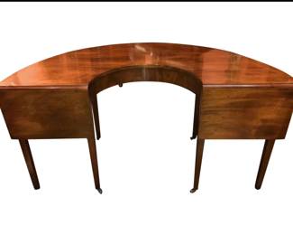 rare drop-leaf HUNT TABLE is an exceptional example of Regency-period cabinetmaking. Also known as a social table, the horseshoe-shaped furnishing was specially designed for serving beverages following a shoot or fox hunt. The horseshoe-shape allowed the table to be set facing a fireplace so the hunters could warm wet and cold feet.