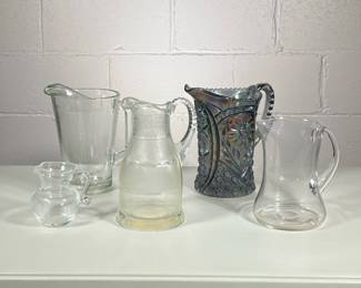 (5pc) Glass Pitchers | Including two blown glass pitchers, one non-descript, one etched glass, and a vintage carnival smoky cut glass pitcher. - h. 9 x w. 6 x l. 9 in