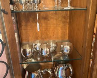 Collection in breakfront of pitchers and a variety of goblets