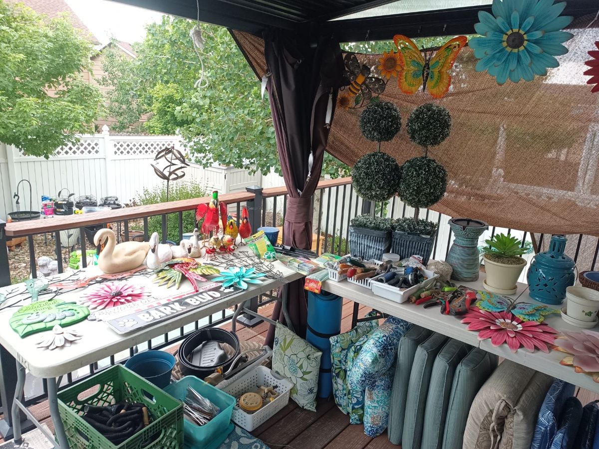 A patio full of yard art, topiary, cushions and planters