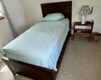 A twin bed with end table and lamp.