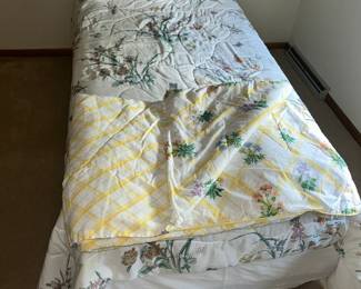 Twin bed with a couple comforters.