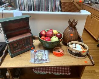 doll cabinet, vintage bowl of ceramic apples, basket of ceramic eggs, wooden pineapple