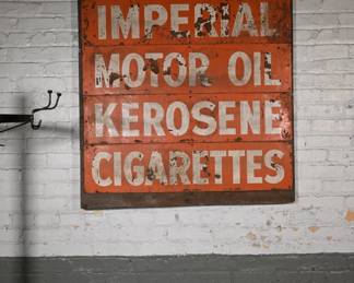 This striking, industrial-era metal sign once advertised the daily specials at a roadside filling station or general store. Featuring bold white block lettering on a vivid, weather-worn orange background, it reads:
“TODAY SPECIAL
IMPERIAL
MOTOR OIL
KEROSENE
CIGARETTES”
The surface exhibits a well-aged patina with chipping paint, oxidation, and surface rust consistent with authentic mid-20th century outdoor signage. The typography and design suggest a production date between the 1940s and 1960s, possibly Canadian or Upper Midwest in origin due to the use of “Imperial” oil branding.
The sign is mounted on a wood backing and retains a gritty, timeworn appeal—ideal for collectors of petroliana, industrial décor, Americana, or the macabre, given its nostalgic nod to a grittier, more visceral era of commerce.