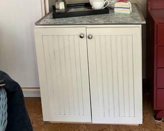 White bead-board cabinet with protective vinyl top and a 3 slated wooden mail wall hanging and a canvas print of a bike awaiting its rider (24x24)