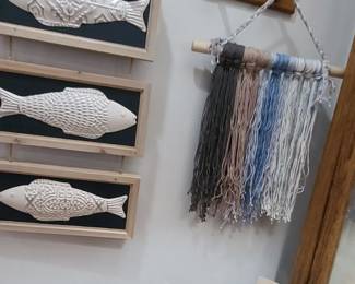Wall hangings of various types - 3 framed ceramic fishes, yarn art, and a framed lighthouse message.  Plus, a wooden carved coat rack and a unique wooden 'door bell' chime