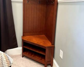 Corner cupboard with coat hooks and storage shelves.