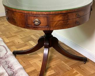 Georgian Style Mahogany Drum Table | Vintage (mid 20th c.) Georgian style mahogany drum table, with tooled leather top, fitted glass, and one frieze drawer on four saber legs with casters. - h. 29 x w. 34 in