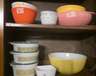 Close up of mixing bowls in various sizes & colors kitchen cabinet - both shelves - top shelf has more mixing bowls.