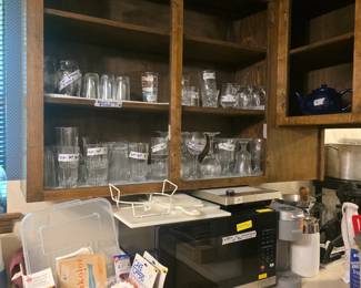 More glasses sets in cabinet, microwave, Keurig, cutting boards, miscellaneous cake decorating items