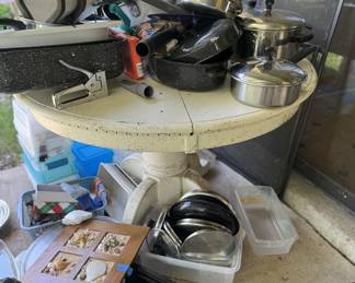 Round White Table Covered with Pots and Pans and miscellanous items