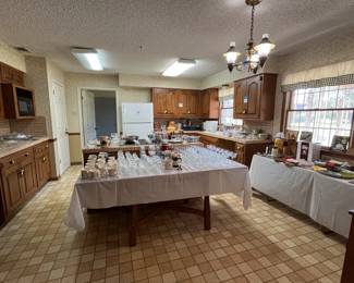 Kitchen tables and countertops covered with dishes, gadgets, glassware, etc
