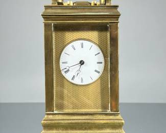 “AB” BRASS CARRIAGE CLOCK | Heavy, with beveled glass panels, white face set in a brass engine turned panel, having Roman numeral markers, the back panel signed “AB” with a star within an oval - h. 6 x w. 3.5 x d. 3 in
