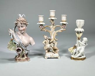 (3pc) Porcelain Pieces | Bust of woman draped with flowers. Candle stick holder with cherub and French candelabra with gentleman sitting at the bottom. Cherub Candlestick holder is marked. - h. 10.25 x w. 7 in (French candelabra)
