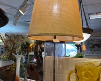 Glass lamp with burlap shade and metal details.