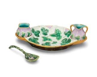 1038
Late 19th/early 20th century; England
A George Jones majolica pottery strawberry server
Tray marked in black to unglazed patch at underside: 2243 / G
The glazed earthenware set, each with strawberry leaves in relief, comprising an open sugar (, a creamer (3.615" H x 3.375" W x 2.875" D), and a ladle (7.5" L), all set in a tray (2" H x 14.25" W x 8.75" D)
4 pieces
Estimate: $300 - $500