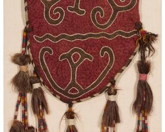 1259
Early 20th century; Central Asia
An Uzbek "ok bash" embroidered wool tent pole bag
The conical ok bash (uuk bash) or tent bag of red wool felt with one folded edge, featuring brown and white wool curvilinear embroidered designs, the open edges trimmed with red and multicolored wool chain-stitch embroidery and seam edges trimmed with bands of black and white wool herringbone stitches, all adorned with five strands of multiple horsehair tassels bound in multicolored fabric strips and thread, professionally mounted and framed under Plexiglas
44" H x 13.5" W (including tassels) approximately
Estimate: $300 - $500