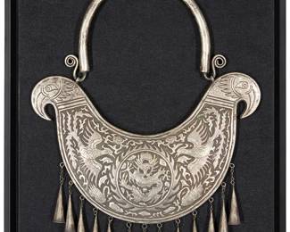 1258
20th century; Southeast Asia
A Hmong Miao collar necklace
A two-piece silver-toned metal articulated hollow collar with incised repoussé decoration featuring a central dragon roundel flanked by various birds and other auspicious motifs, with a bird head motif to each side point, and the lower edge with chunky cone dangles, mounted in a shadowbox-style frame
18.5" H x 14.5" W
Estimate: $200 - $400