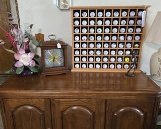Wood Pennsylvania House Server Cabinet; Collection of Golf Balls in Wood Display; Silk Flowers; Two Howard Miller Battery Operated Clocks