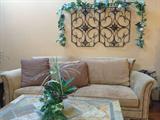 American Signature comfy sofa, iron and stone coffee table, and iron wall decor