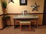 Yamaha keyboard, piano bench, wall decor, and corner table with vase