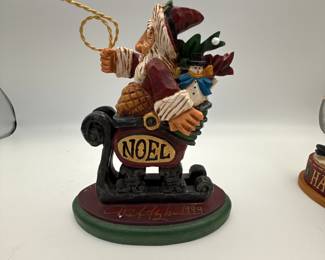 David Frykman Santa Figures. Included are: a whimsical Santa with a 'NOEL' sign, a festive Santa with a puppy, and a cheerful Mrs. Claus with gift-laden sled. Each piece captures the joy of the holiday season.