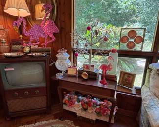 Those are lawn flamingoes that light up! They work…I like that shell art in the window, very classy…And the bright and cheery table floral/candle piece under the table…