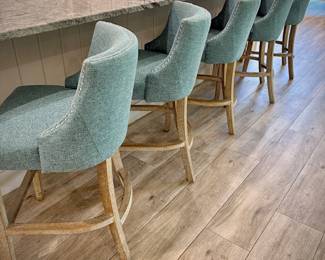 Five turquoise upholstered barstools. Seat height is 24 inches. Wood leg legs with metal kick bar.