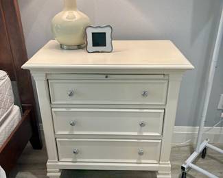 One of two white night stands, each with three drawers and pullout tray