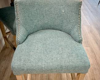 Five turquoise upholstered barstools. Seat height is 24 inches. Wood leg legs with metal kick bar.
