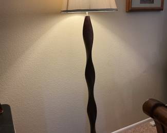 Floor lamp with graceful curved wood pole.