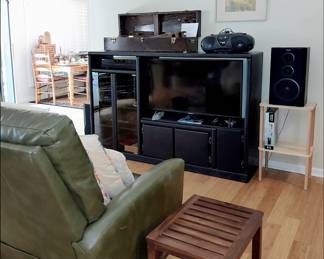 Entertainment Center with Stereo and TV. There is an old toolbox on top that is holding 4 antique saws made by Henry Disston, and an antique grease gun.