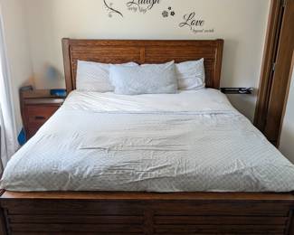 King size bed with end table and lots of linen pillows, mattress, blankets and comforters