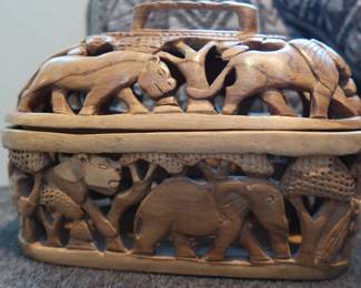 Hand-Carved Wooden Safari Basket
Intricately carved lidded basket featuring elephants, lions, and other wildlife. Lightweight, likely teak or acacia wood. Decorative and functional—use as a bread basket, trinket box, or display piece.
Approx. 8" long
Lid lifts off, carved on all sides